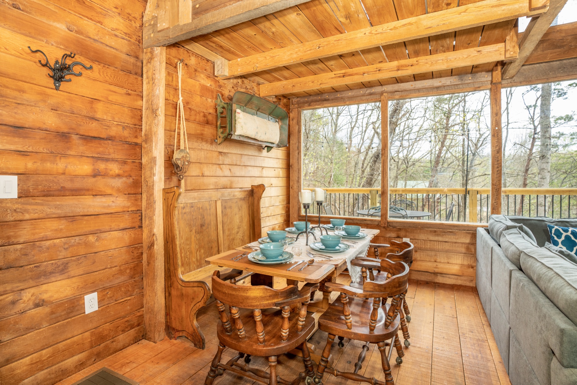 Dining nook at Rustic Retreat set with teal dishware, candlesticks, and a wall of windows